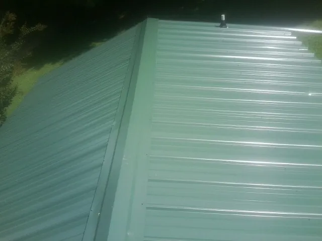 New green metal panels meeting at the ridge of a roof — Flat Roof Repair work by our crew in New Park