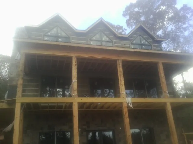 Dormers and porch framing on a large log home under construction — Roof Coating work by our crew in New Park