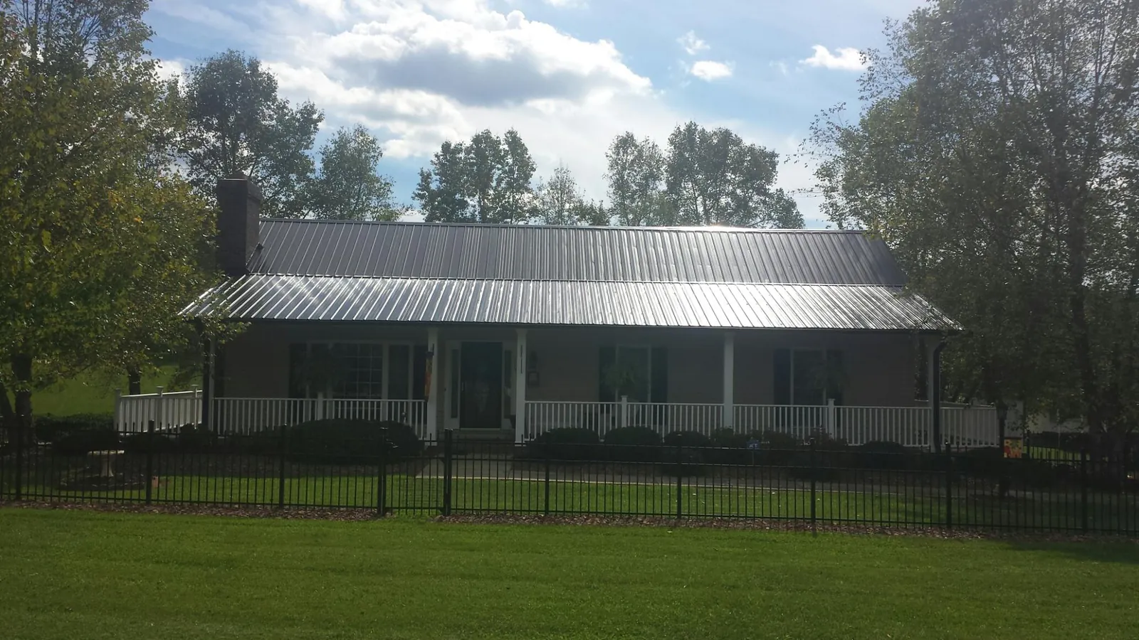 Gray metal roof on a brick ranch with a full width front porch — Gutter Guard Installation work by our crew in New Park