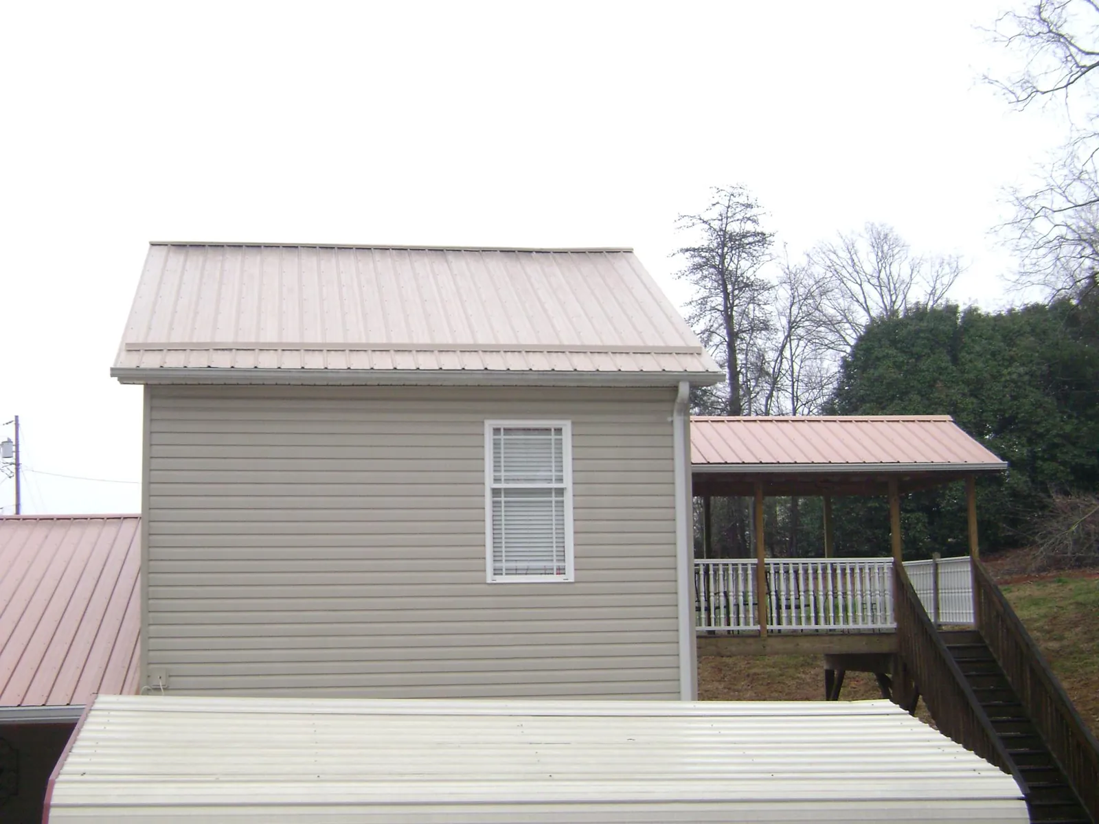Tan metal roofs on a two story addition and attached porch, from a Roof Replacement job in New Park