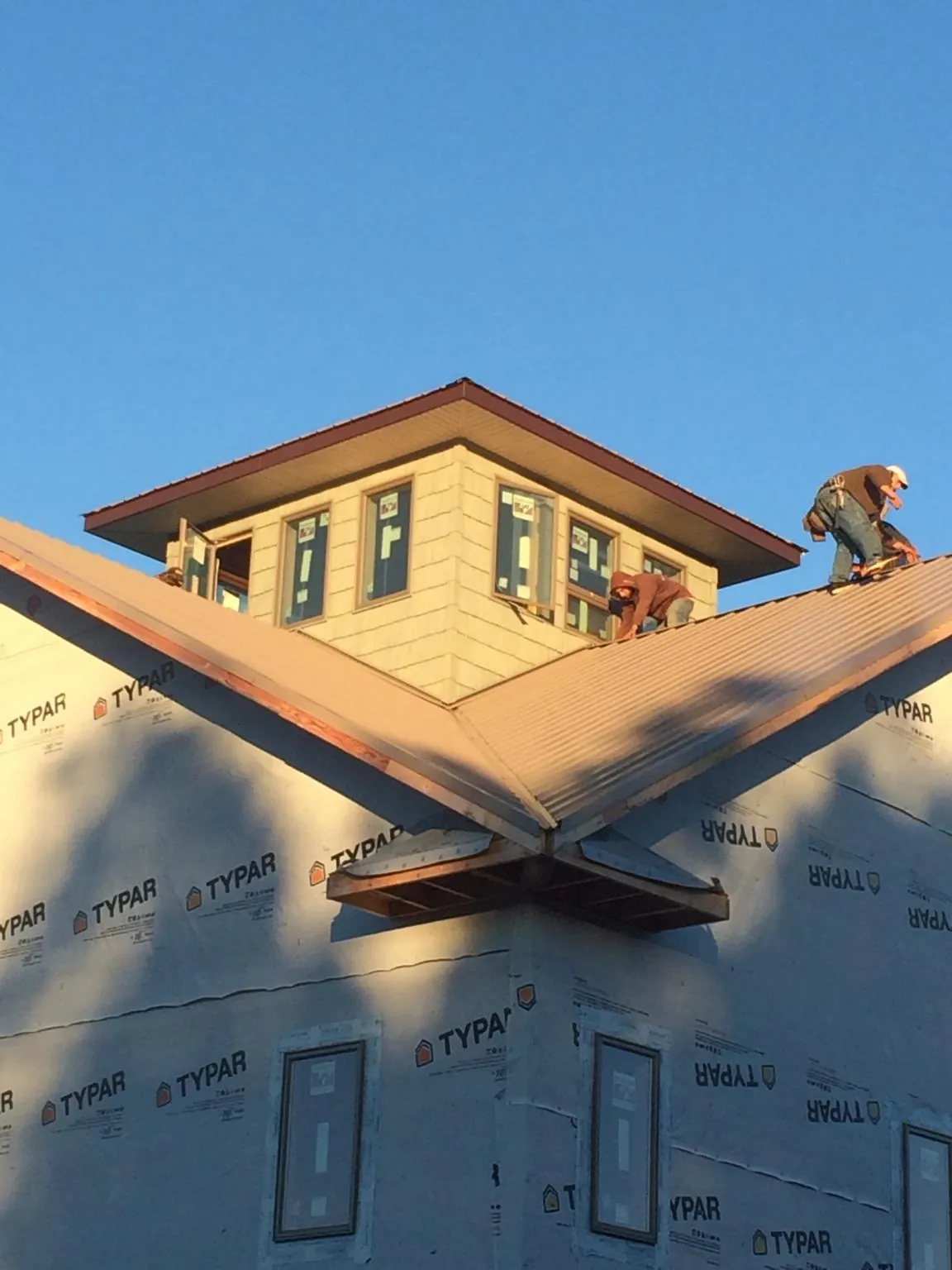 Roofers working around a rooftop cupola on a new metal roof at sunset — Roof Waterproofing in New Park by Roofing Brothers